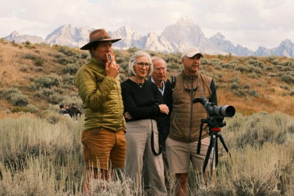 four-people-observe-mountains-from-a-grassy-field-.jpg Four people observe mountains from a grassy field.